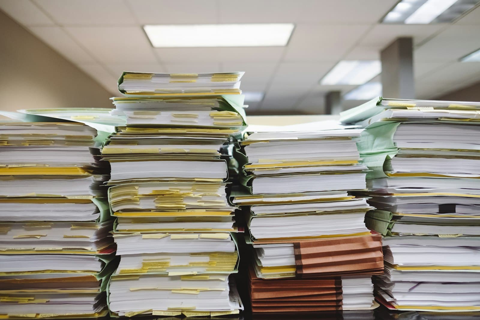 Tall stacks of printed documents and folders in an office